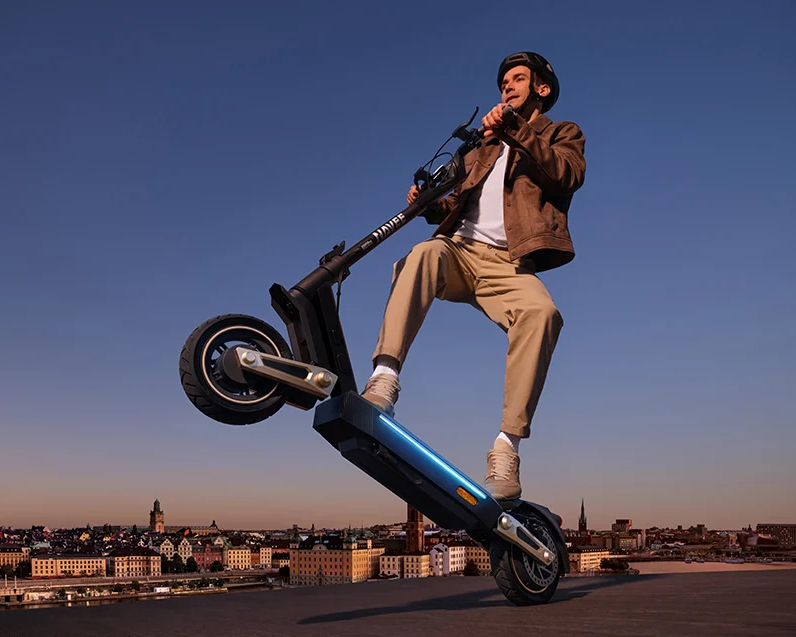 Mężczyzna w kasku wykonuje manewr na hulajnodze elektrycznej NAVEE ST3 Pro z zawieszeniem Damping Arm
